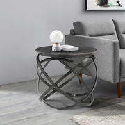 Moderner Beistelltisch mit schwarzer runder Tischplatte und kunstvollem Metallgestell, seitliche Perspektive.