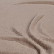Nahaufnahme eines beigen Spannbetttuchs mit weicher Textur und Falten.
