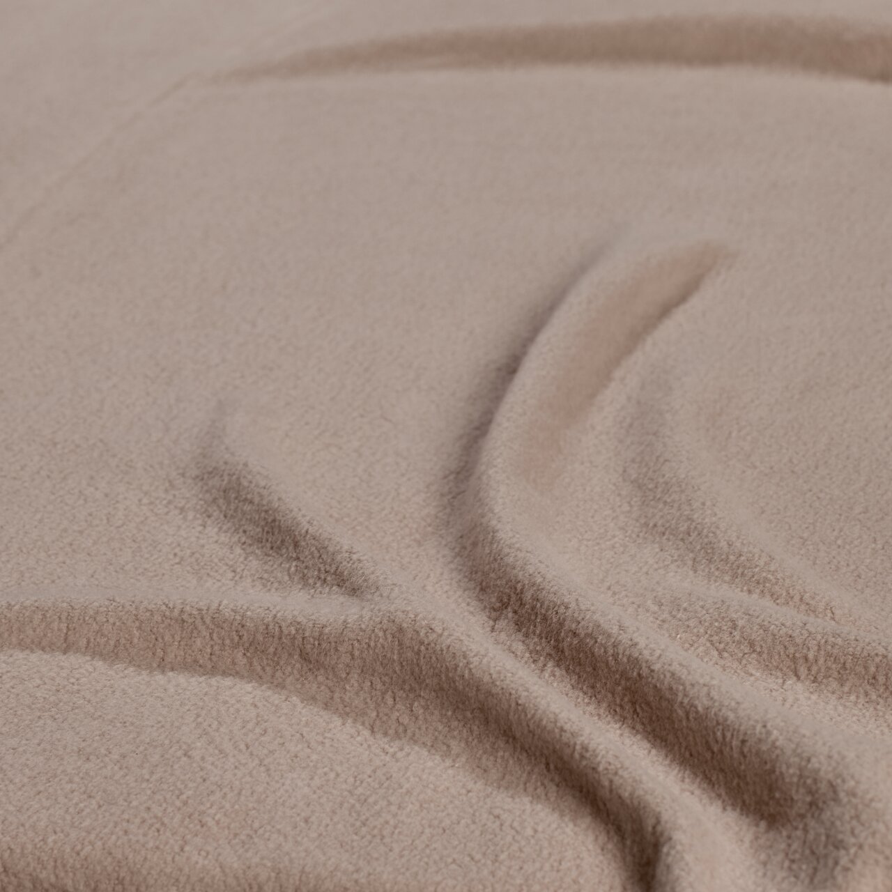 Close-up van een beige hoeslaken met een zachte textuur en plooien.