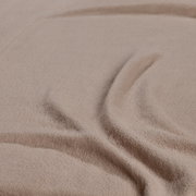 Nahaufnahme eines beigen Spannbetttuchs mit weicher Textur und Falten.