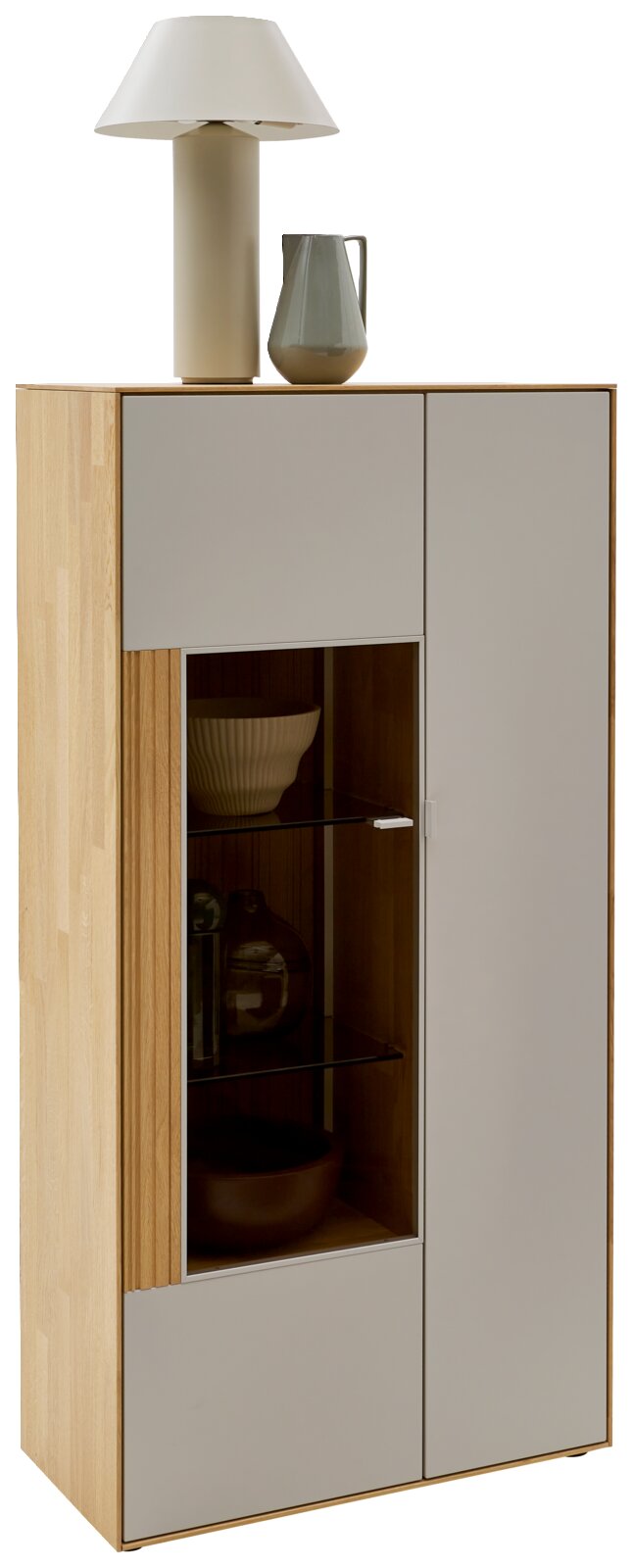 Modernes Highboard/Vitrine aus hellem Holz mit grauen Fronten und Glastür, auf der Deckplatte stehen eine Tischlampe und eine Vase; freigestellt in leicht schräger Frontansicht von links.