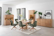 Moderne Esszimmer-Einrichtung mit einer Kombi-Vitrine aus Holz, umgeben von grünen Stühlen und einem Esstisch, aus der Perspektive des Raumes betrachtet.