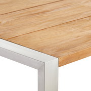 Nahaufnahme eines Gartentisches mit Holzplatte und Metallrahmen, perspektivisch von der Ecke aufgenommen.