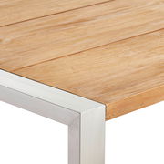 Nahaufnahme eines Gartentisches mit Holzplatte und Metallrahmen, perspektivisch von der Ecke aufgenommen.