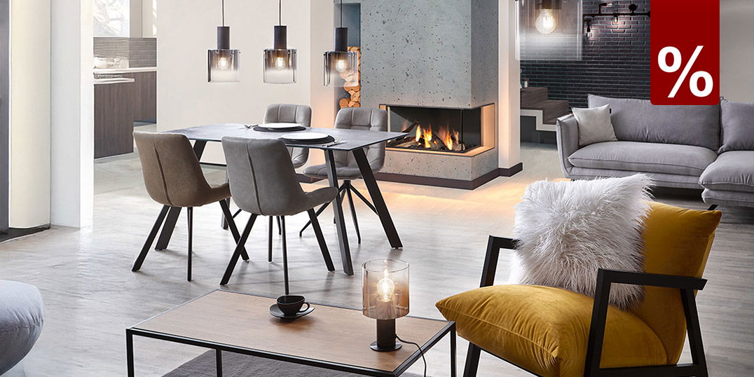 Design-Leuchten im Wohnzimmer: Hängelampen über dem Esstisch, gemütliche Einrichtung mit Kamin und gelbem Akzentstuhl.