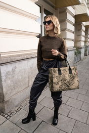 Frau mit Sonnenbrille trägt eine stilvolle, gemusterte Einkaufstasche in der Hand, seitliche Perspektive