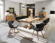 Moderne Esszimmermöbel in einem hellen Raum, bestehend aus einem großen Holztisch mit schwarzem Metallgestell, umgeben von schwarzen Stühlen und einer Bank, mit einem Sideboard und einer Vitrine im Hintergrund. Perspektive: Frontalansicht des Essbereichs.