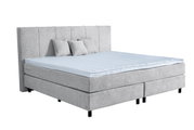 Graues Boxspringbett mit hohem Kopfteil und drei Kissen, seitliche Perspektive