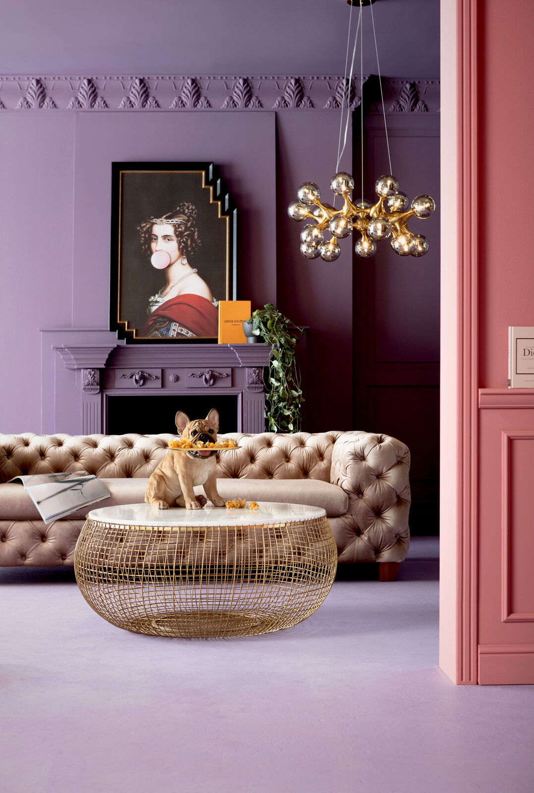 Deko-Figur eines sitzenden French Bulldog Butlers mit Tablett im Maul, auf einem runden Tisch in einem stilvoll eingerichteten Raum mit lila Wänden und einem eleganten Sofa. Perspektive: Frontalansicht.
