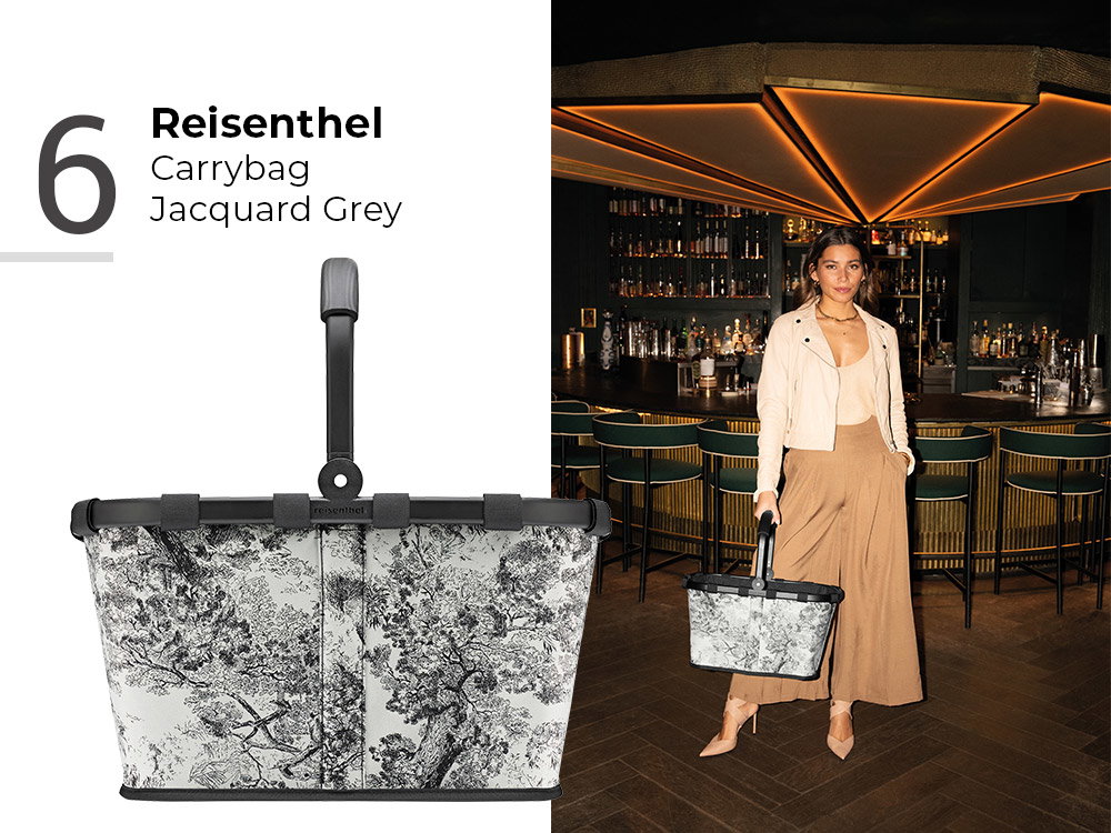 Reisenthel Carrybag Jacquard Grey mit Muster, getragen von Frau in stilvoller Bar-Umgebung