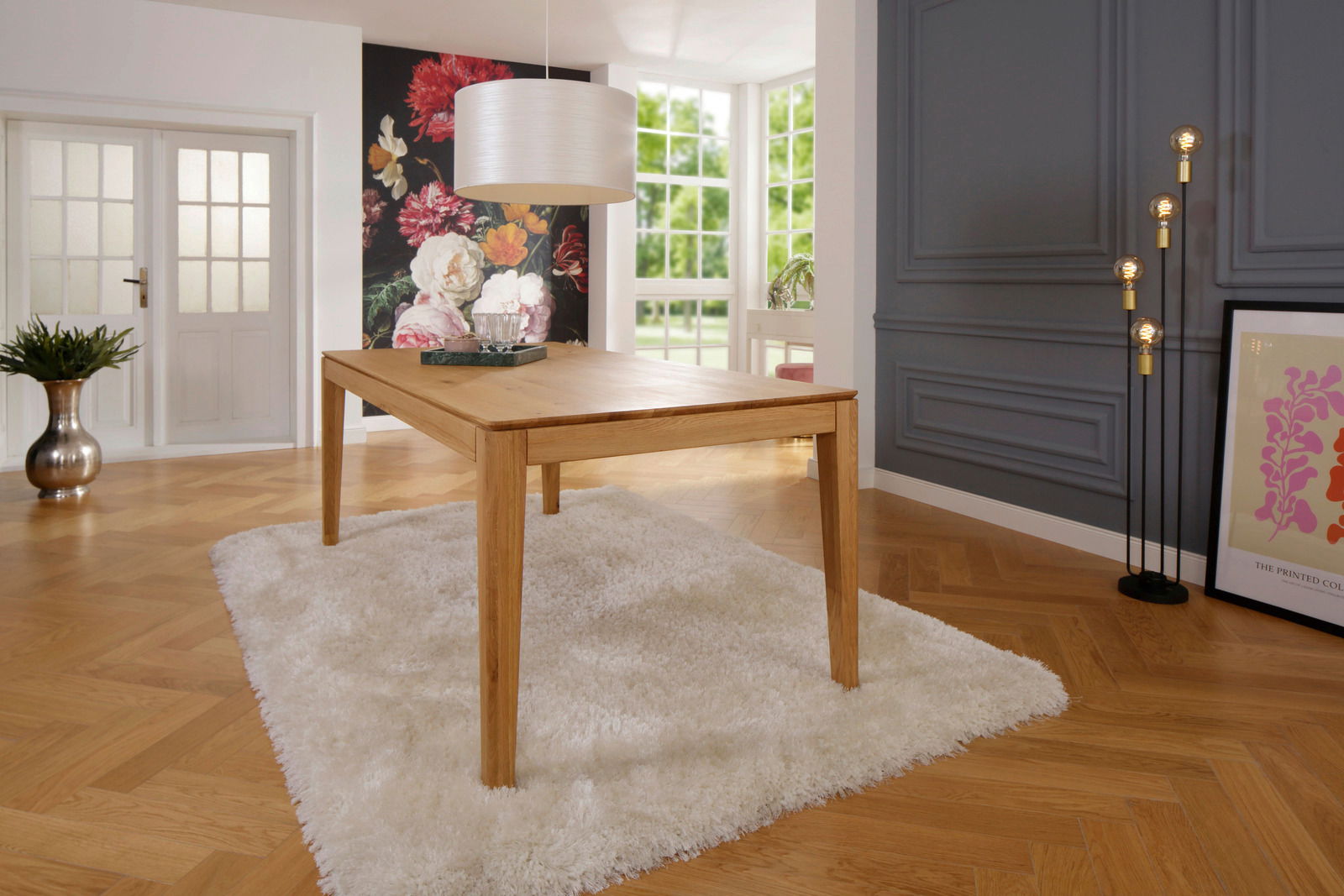 Moderner Esstisch aus Holz in einem stilvoll eingerichteten Raum mit Blick auf eine blumige Wanddekoration und große Fenster.