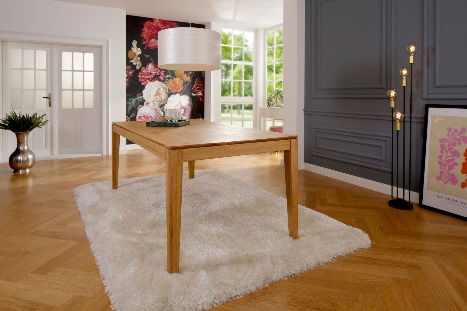 Moderner Esstisch aus Holz in einem stilvoll eingerichteten Raum mit Blick auf eine blumige Wanddekoration und große Fenster.