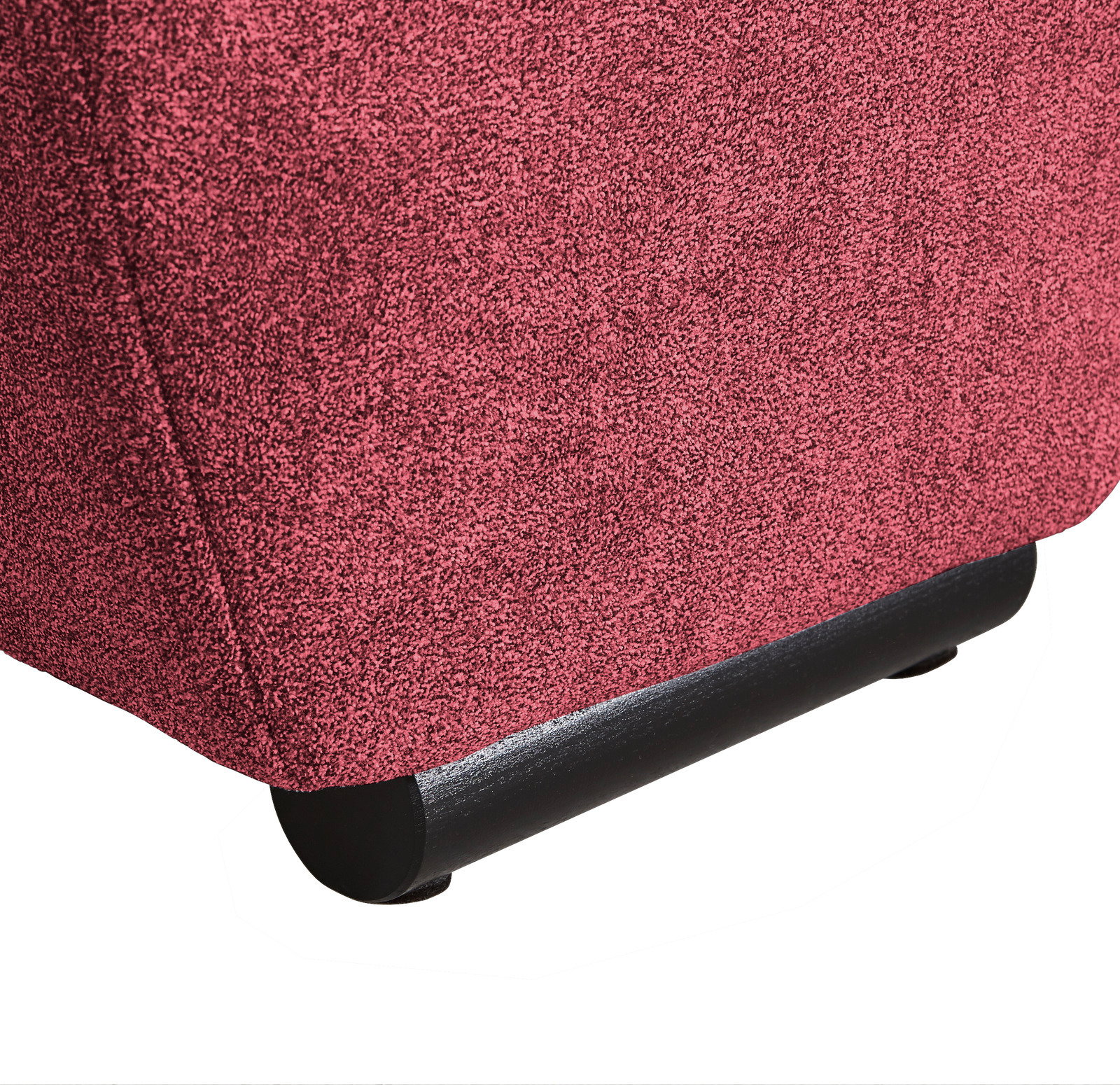 Nahaufnahme der unteren Ecke eines Big-Sofas in rotem Stoff mit schwarzem Fuß, seitliche Perspektive.