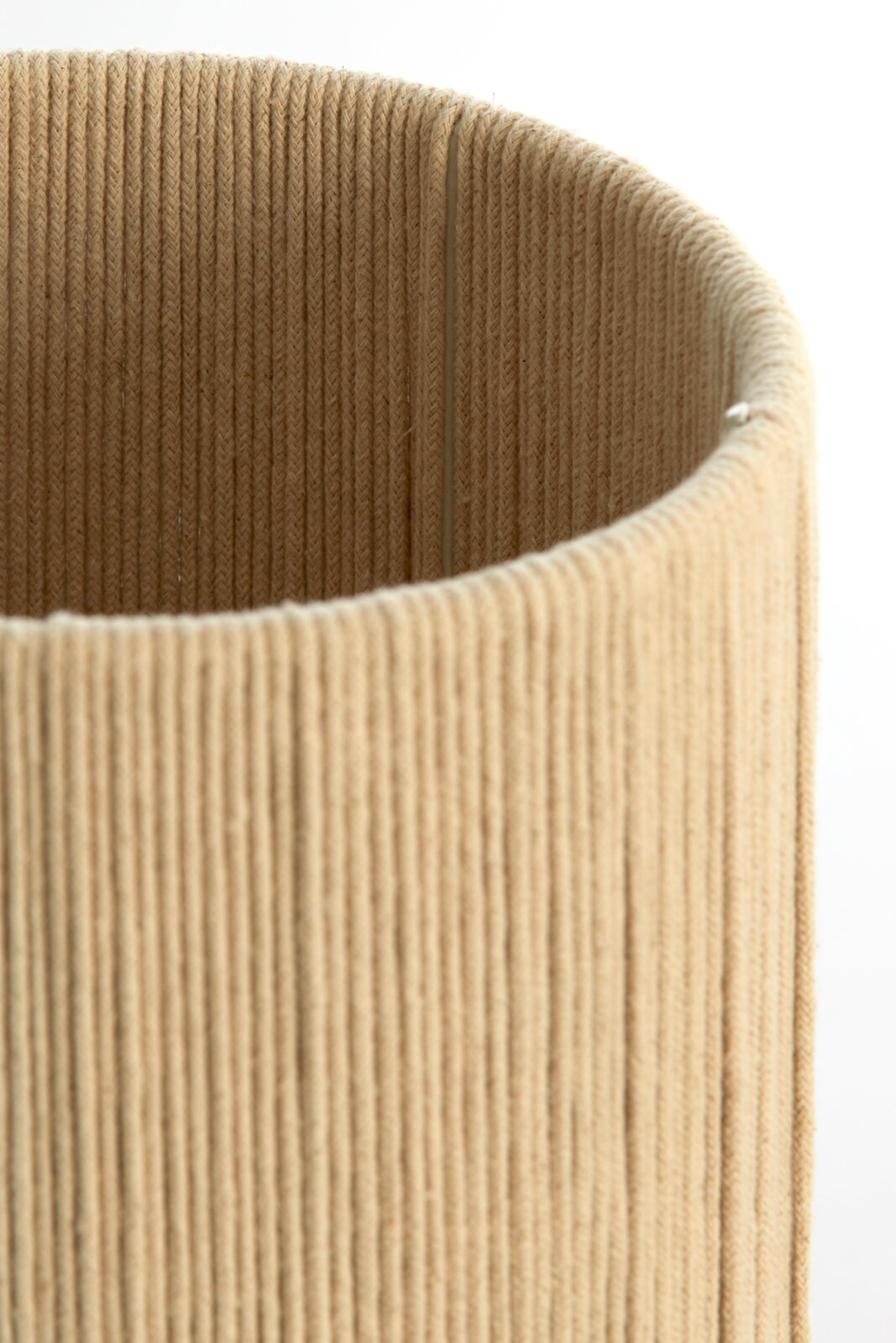 Nahaufnahme eines zylindrischen, beige-farbenen Lampenschirms mit texturierter Oberfläche, von oben betrachtet.