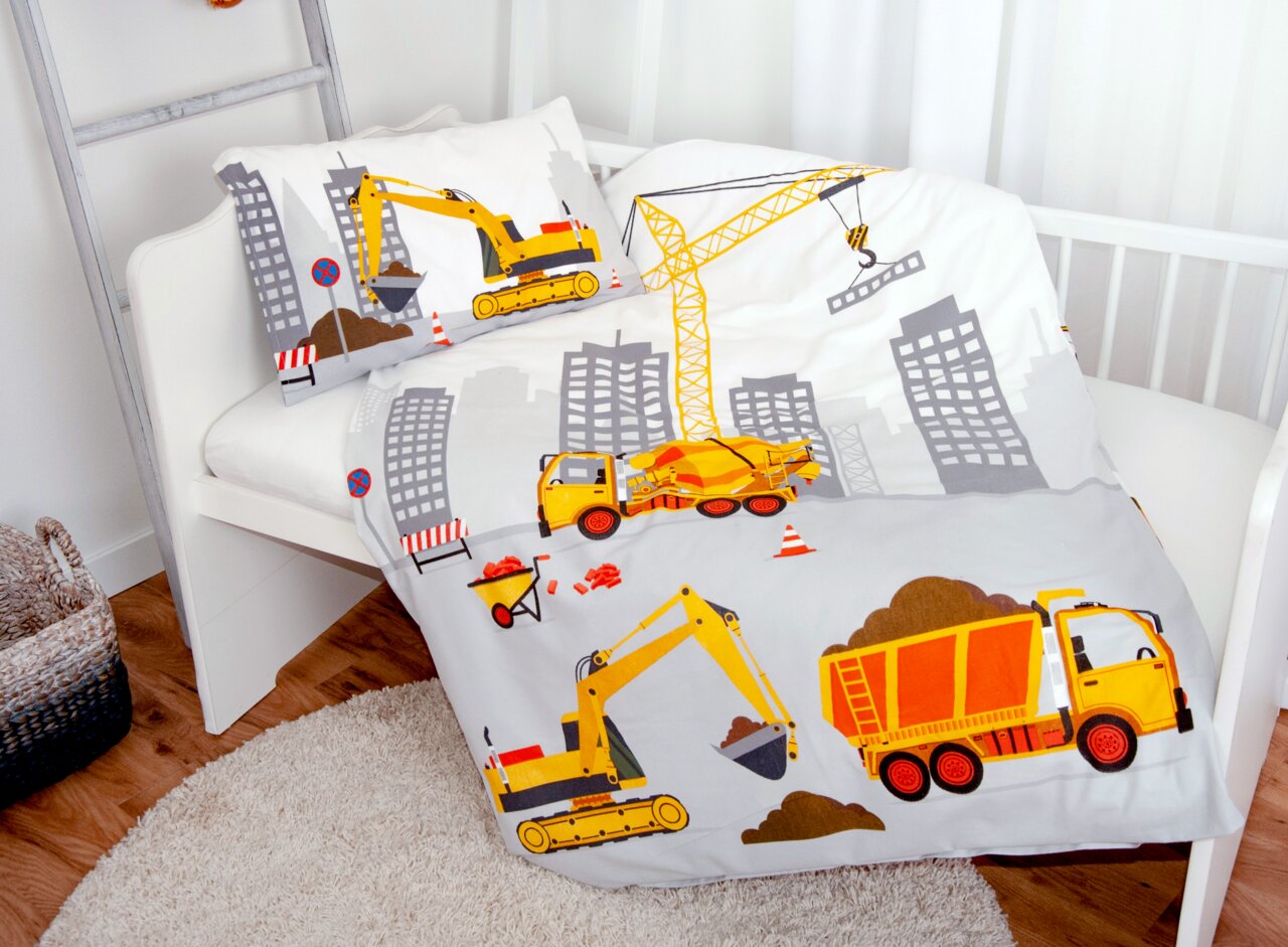 Kinderbettwäsche mit Baustellenmotiv, inklusive Bagger, Kran und Betonmischer, auf einem Kinderbett von schräg oben fotografiert.