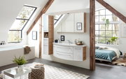 Moderne Badkombination in einem hellen Dachgeschossbad mit Holz- und Weißtönen, bestehend aus einem Waschtisch mit Schubladen und einem Spiegelschrank, seitliche Perspektive.