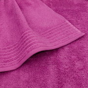 Close-up van een roze badstofhanddoek met geweven rand en omgeslagen hoek, gezien van bovenaf vanuit een licht schuin perspectief