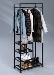 Garderobenwagen aus schwarzem Metall mit mehreren Regalböden und Kleiderstange, darauf hängen Jacken und Mäntel; Schuhe und eine Mütze sind auf den Regalen platziert. Perspektive: Frontalansicht.