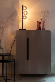 Moderne Tischleuchte mit drei leuchtenden Glaskugeln auf einem schwarzen Ständer, seitliche Perspektive.