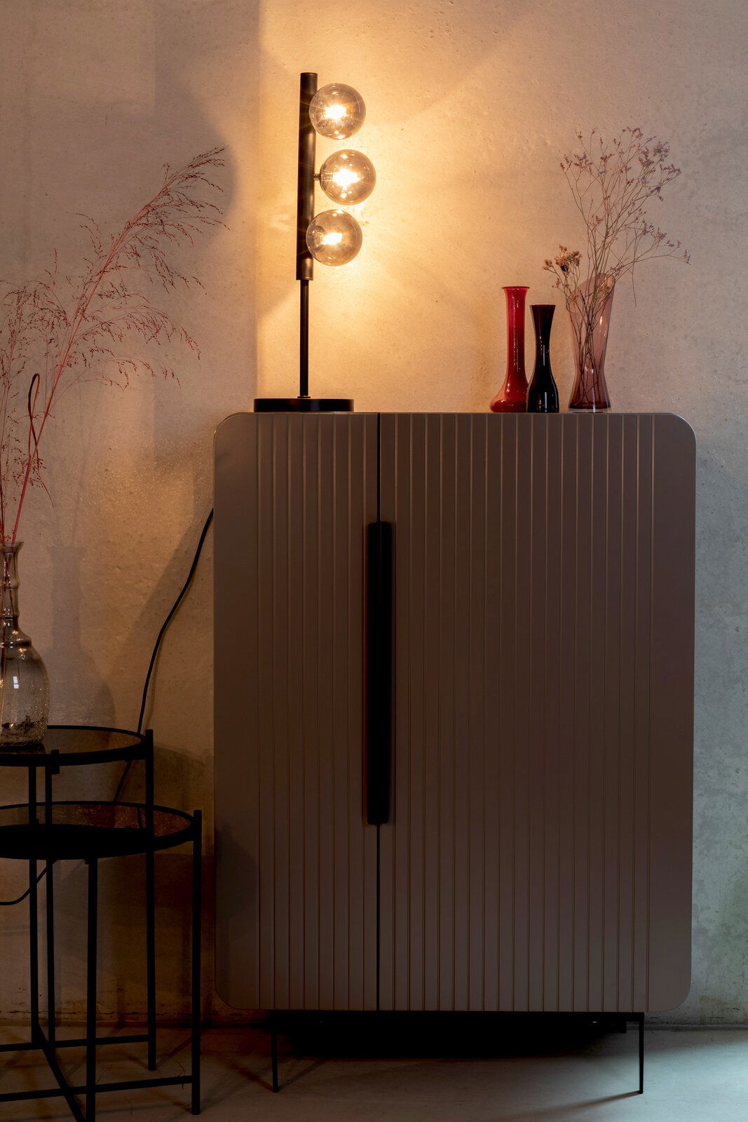 Z2 Tischleuchte MONICA Moderne Tischleuchte mit drei leuchtenden Glaskugeln auf einem schwarzen Ständer, seitliche Perspektive.