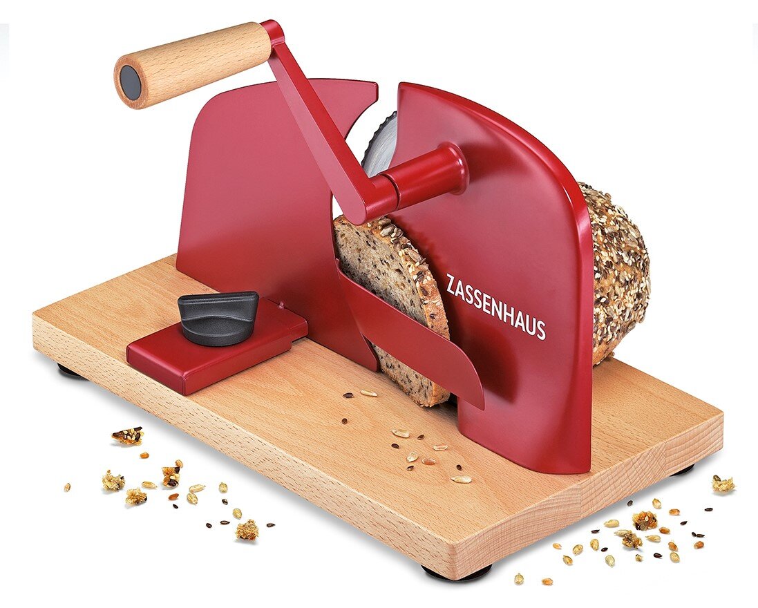 Roter Zassenhaus Brotschneider mit Handkurbel und Holzsockel, schneidet ein Körnerbrot; Perspektive: schräg von vorn links (3/4-Ansicht)