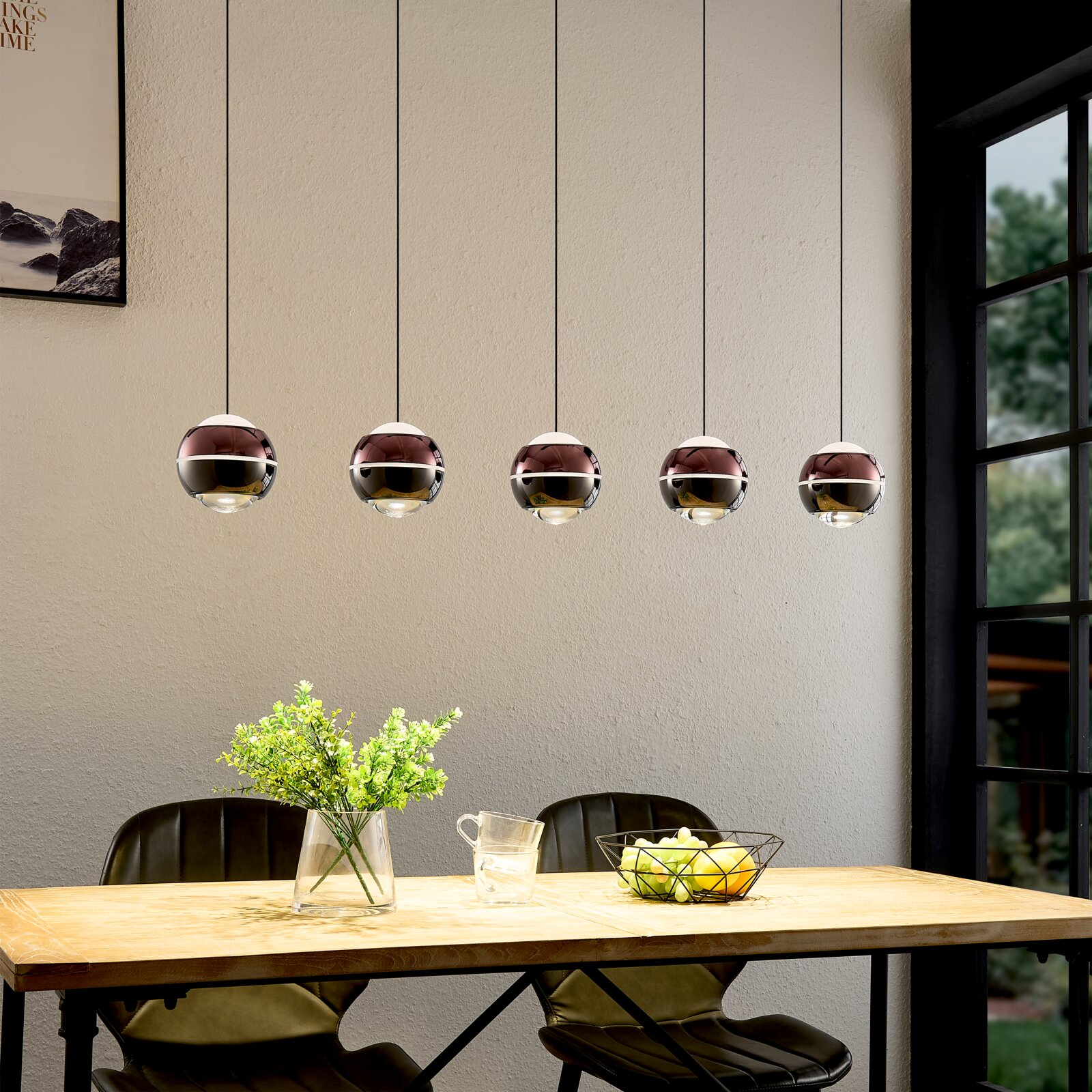 Moderne Pendelleuchte mit fünf kugelförmigen, spiegelnden Glasschirmen in Roségold/Chrom über einem Esstisch, frontale Innenraumansicht auf Augenhöhe