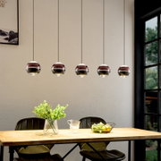 Moderne Pendelleuchte mit fünf kugelförmigen, spiegelnden Glasschirmen in Roségold/Chrom über einem Esstisch, frontale Innenraumansicht auf Augenhöhe