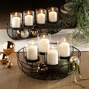 Dekokranz mit schwarzen Metallrahmen, weißen Kerzen in Glaszylindern und goldenen Kugeln, aus der Vogelperspektive fotografiert.