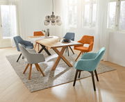 Esszimmer mit modernem Holztisch und verschiedenen bunten Sesseln, fotografiert aus einer leicht erhöhten Perspektive.