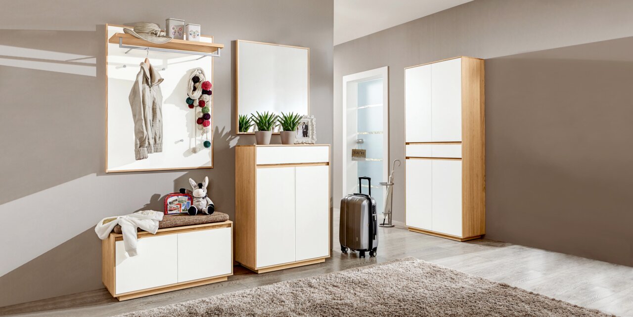 Moderne Garderobeneinrichtung mit Holz- und Weißelementen, bestehend aus Garderobenbank, Schuhschrank, Spiegel und Garderobenpaneel, seitliche Perspektive.