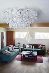 Großer, eleganter Kronleuchter aus klarem Kristallglas in einem stilvollen Wohnzimmer, von unten betrachtet.