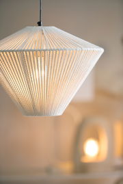 Nahaufnahme einer modernen Hängeleuchte mit weißem, texturiertem Schirm, der von oben betrachtet wird.