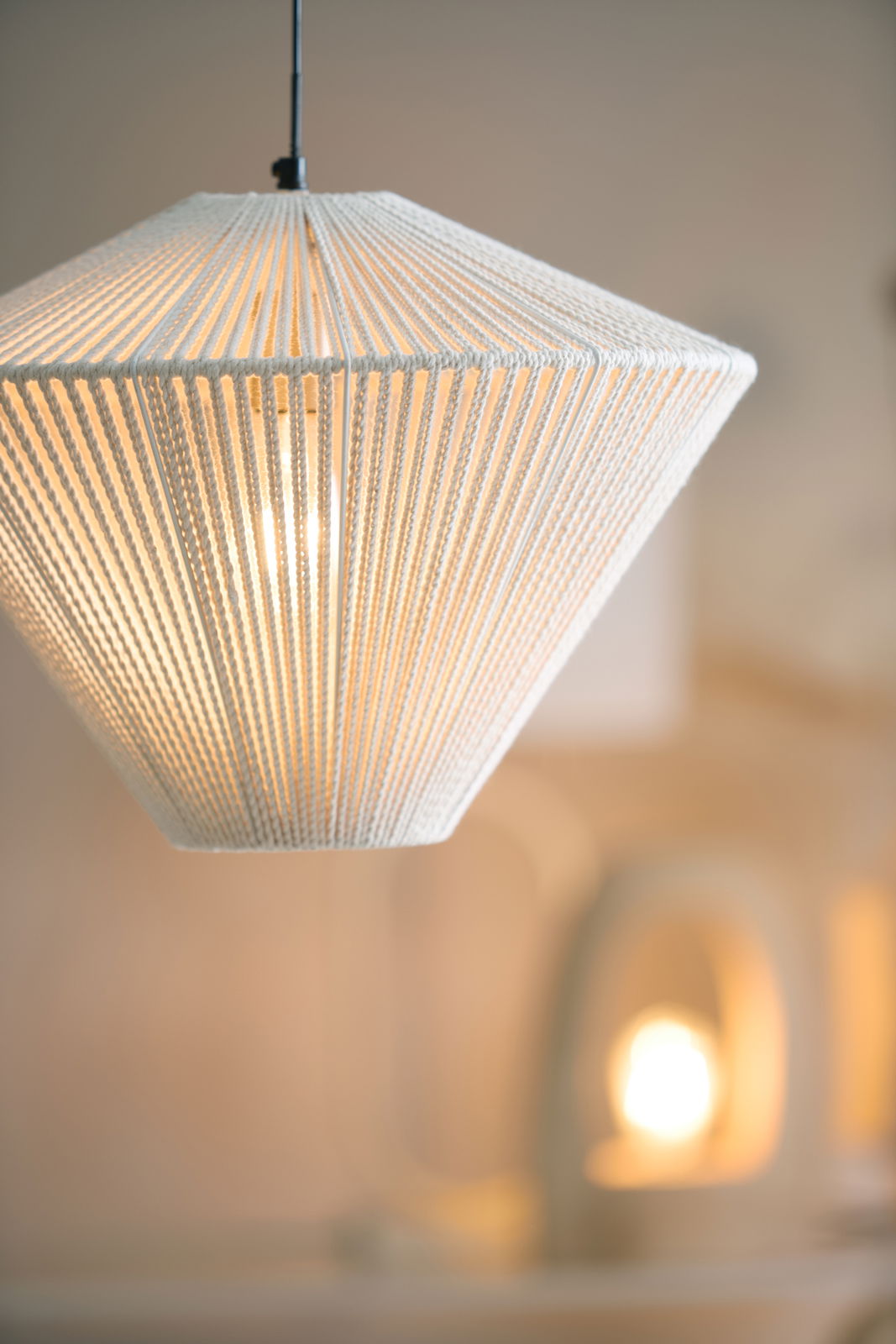 Nahaufnahme einer modernen Hängeleuchte mit weißem, texturiertem Schirm, der von oben betrachtet wird.