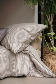 Bettwäsche mit feinen Streifen in einem gemütlichen Raum, seitliche Perspektive