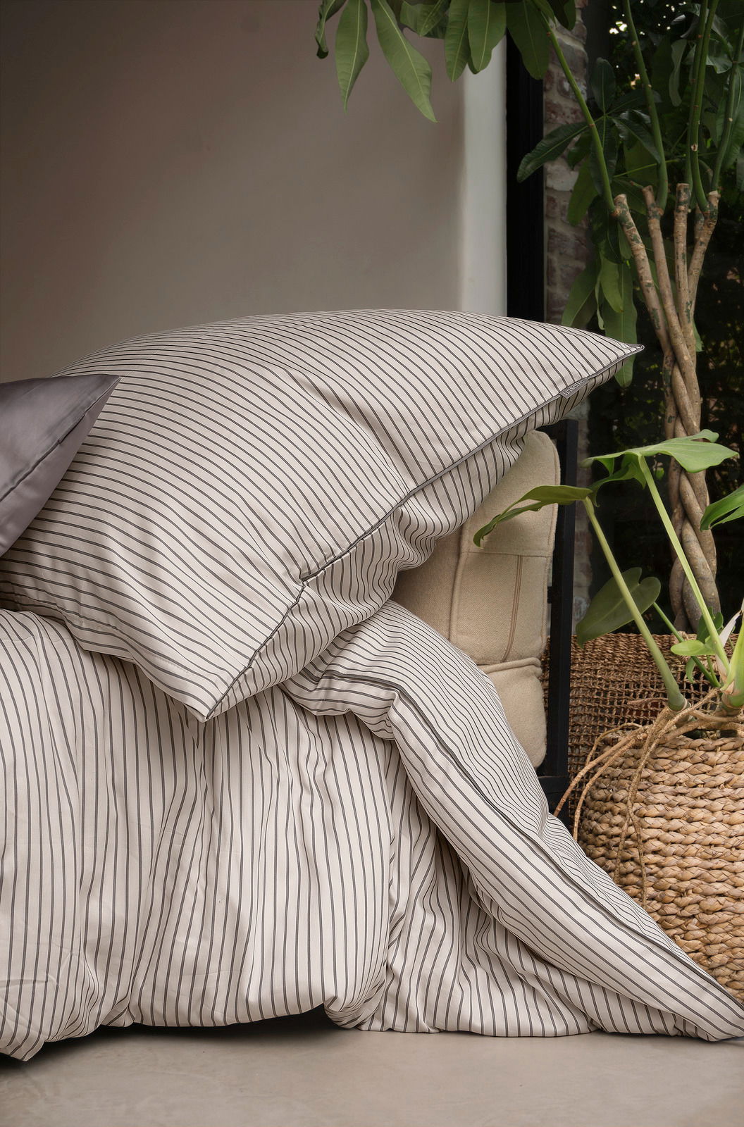 Bettwäsche mit feinen Streifen in einem gemütlichen Raum, seitliche Perspektive
