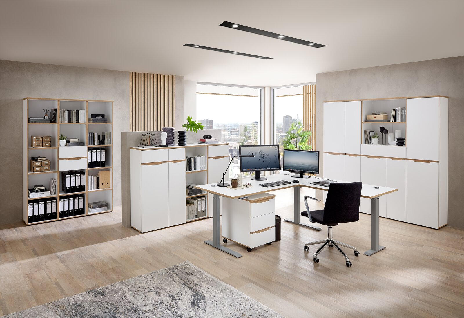 Moderne Büromöbel in einem hellen Raum mit Schreibtischen, Aktenschränken und Regalen, aus der Perspektive eines Betrachters im Raum.