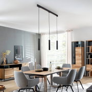 Moderne schwarze 3-flammige Pendelleuchte mit schlanken zylindrischen Lampenkörpern über einem Esstisch in hellem Esszimmer, Perspektive: leicht von unten in der Raumansicht