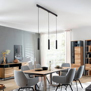 Moderne schwarze 3-flammige Pendelleuchte mit schlanken zylindrischen Lampenkörpern über einem Esstisch in hellem Esszimmer, Perspektive: leicht von unten in der Raumansicht