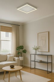 Moderne LED-Deckenleuchte in quadratischer Form, installiert in einem stilvoll eingerichteten Wohnzimmer mit Sofa, Couchtisch und Pflanzen, aus der Perspektive von unten betrachtet.