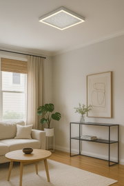 Moderne vierkante led-plafondlamp, geplaatst in een stijlvol ingerichte woonkamer met een bank, salontafel en planten, gezien vanuit een laag standpunt.
