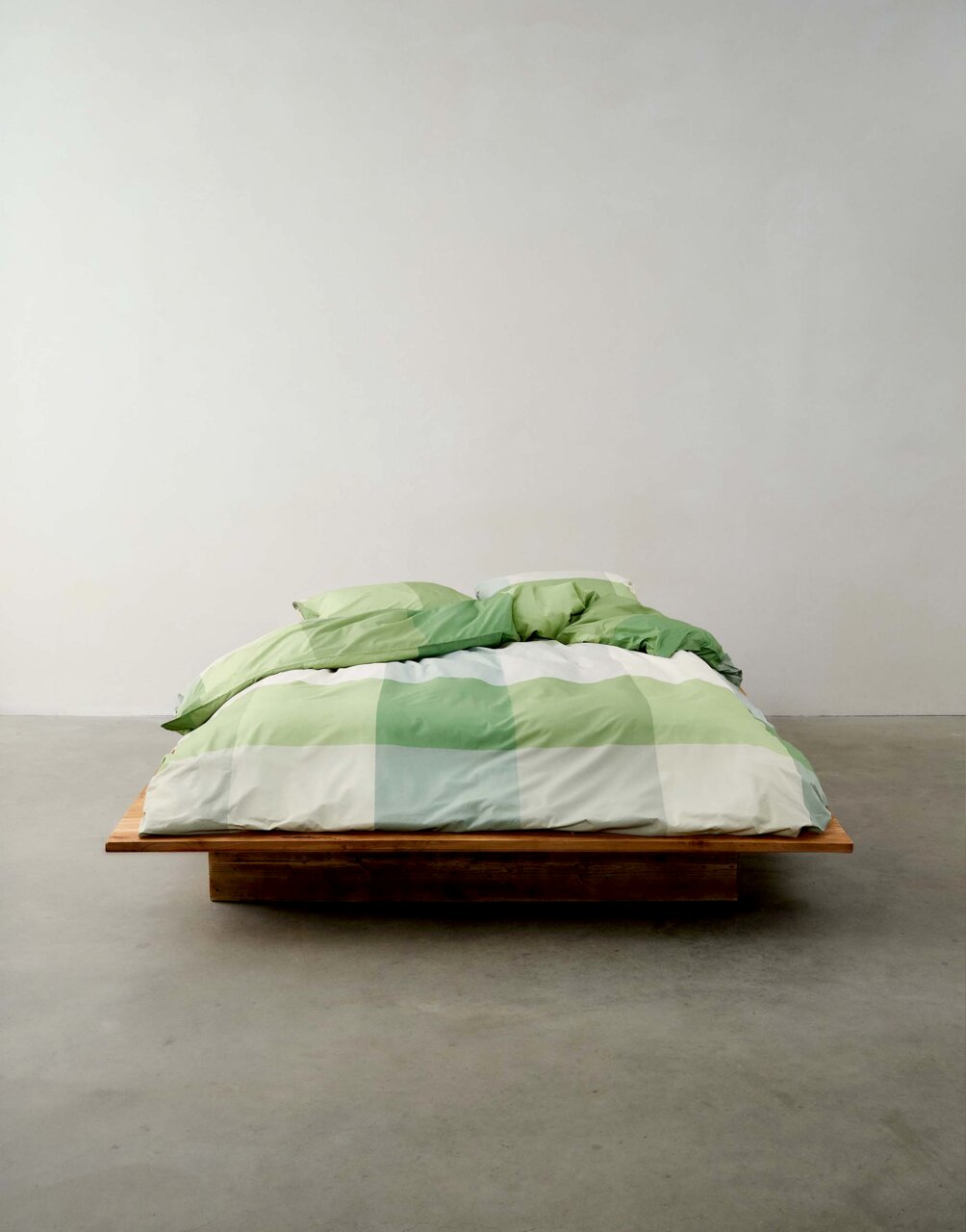 Beddengoed in groene tinten op een houten bed, vooraanzicht