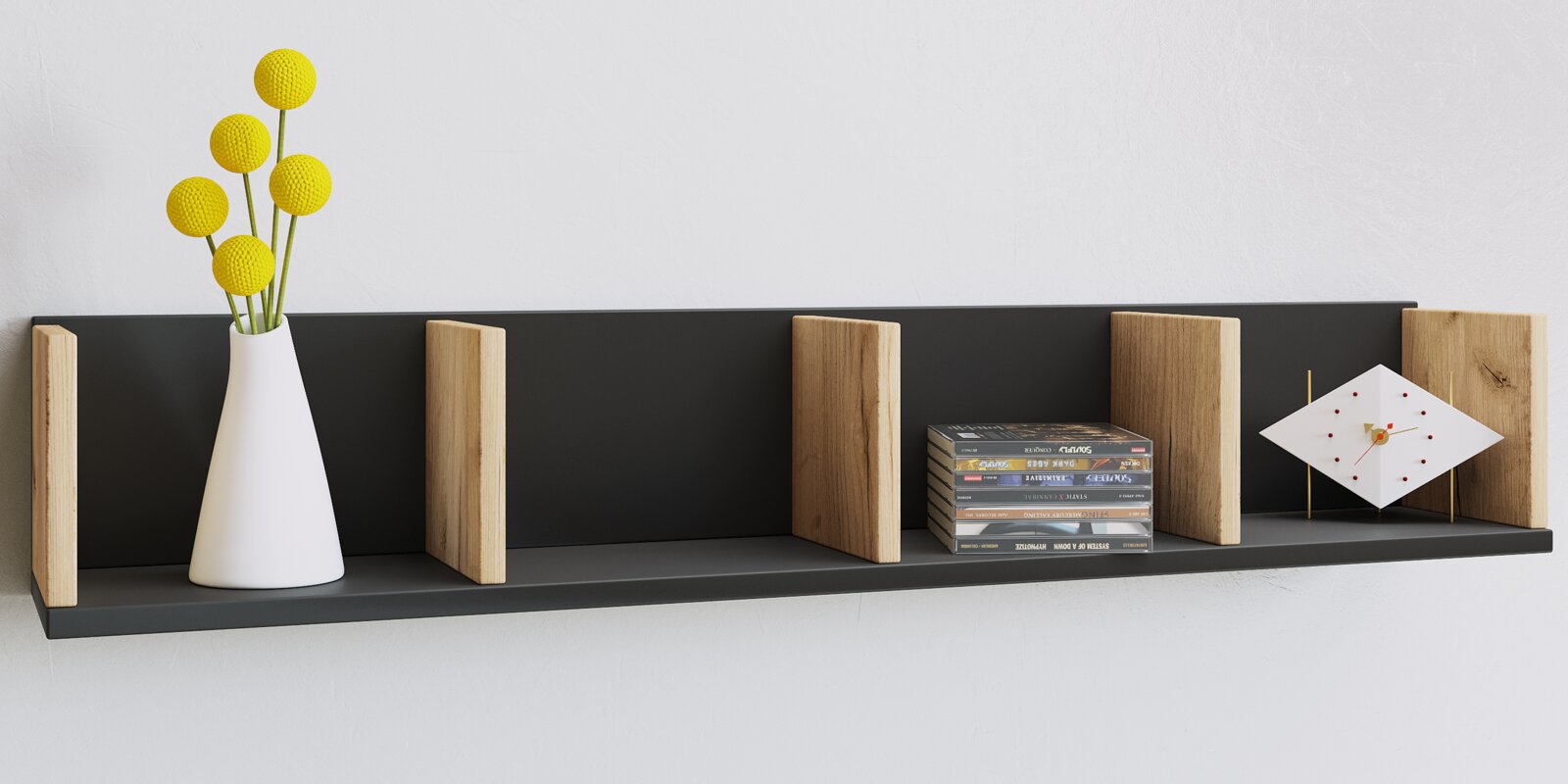 VCM Wandregal HONSA Frontale Ansicht eines modernen Wandregals in Anthrazit mit vertikalen Holztrennern; darauf eine weiße Vase mit gelben Kugelblumen, ein Stapel Bücher und eine geometrische Tischuhr vor heller Wand.