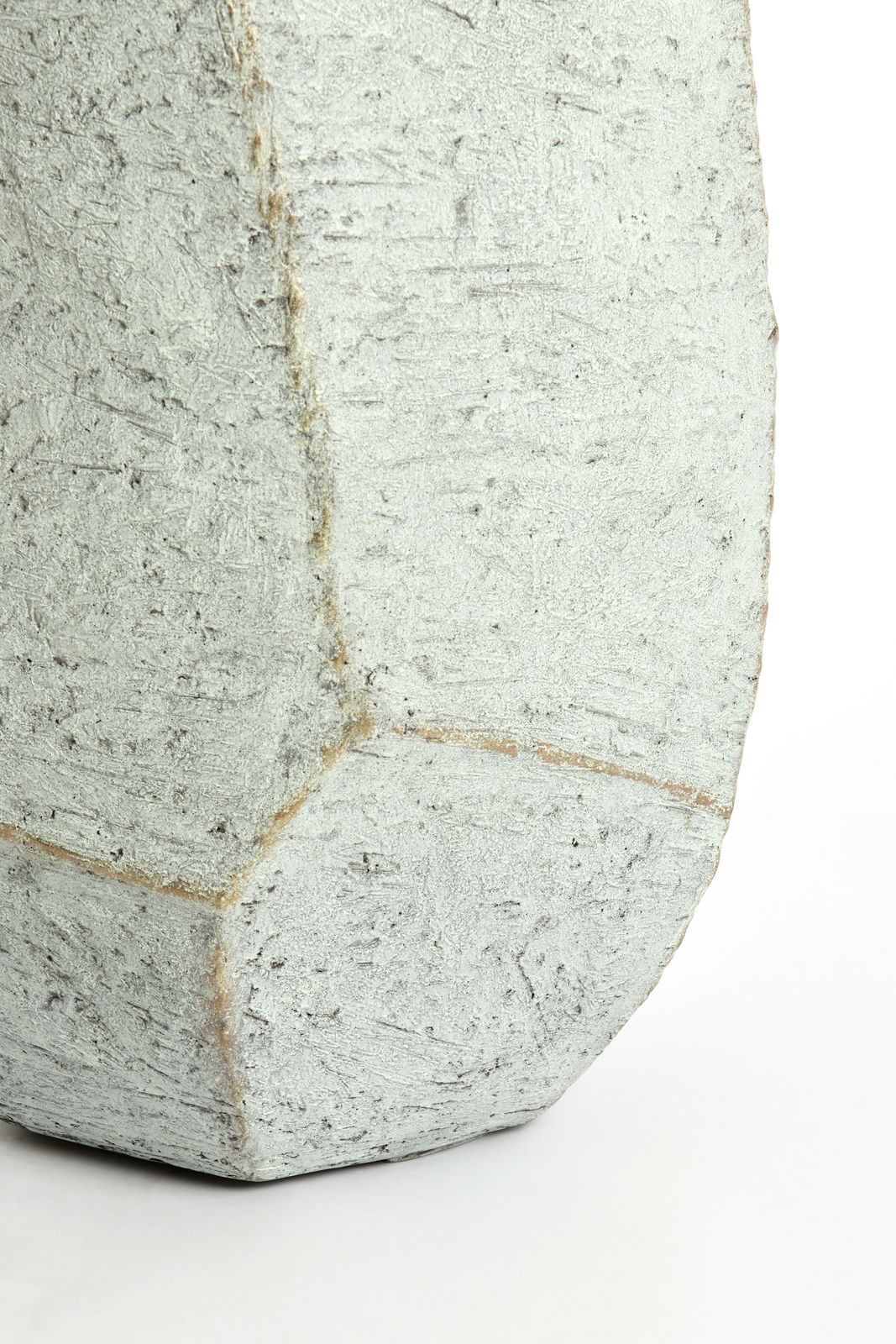 Nahaufnahme eines strukturierten, geometrischen Topfes aus Beton mit rauer Oberfläche.