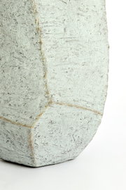 Nahaufnahme eines strukturierten, geometrischen Topfes aus Beton mit rauer Oberfläche.