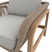 Nahaufnahme eines Lounge-Sessels mit hellgrauem Kissen und einem Rahmen aus hellem Holz, seitliche Perspektive.