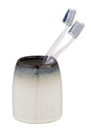 Zahnputzbecher in Braun und Weiß mit zwei Zahnbürsten, seitliche Perspektive