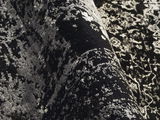 Nahaufnahme eines Designer Teppichs mit abstraktem, schwarz-weißem Muster, aus seitlicher Perspektive aufgenommen.