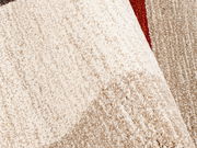 Nahaufnahme eines strukturierten Teppichs in Beige- und Brauntönen mit einem Hauch von Rot, perspektivisch von oben fotografiert.