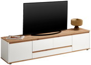 XL-TV-Lowboard in moderner Frontansicht mit weißem Korpus und Holzoberfläche, dekoriert mit einem Fernseher, einer Lampe und Zeitschriften.