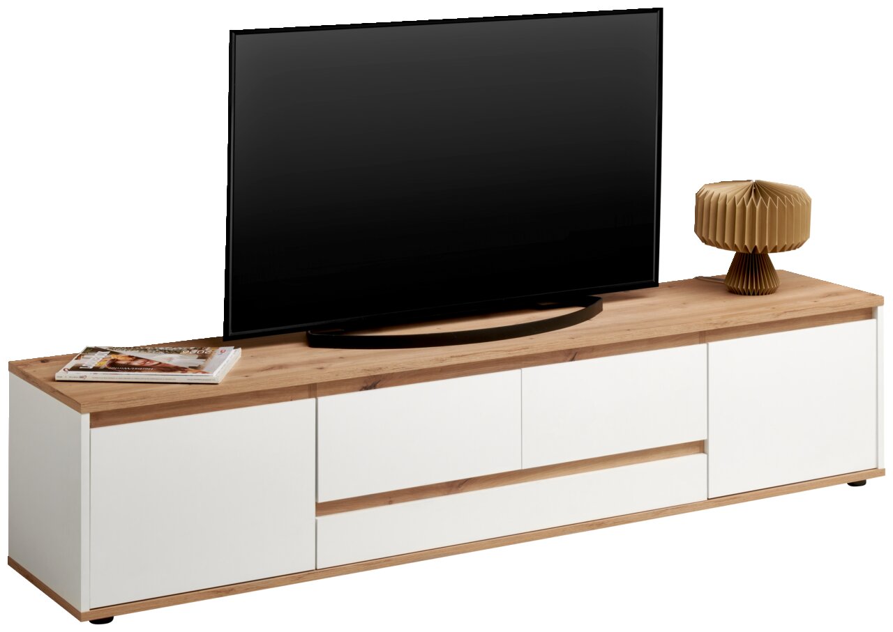 XL-TV-Lowboard in moderner Frontansicht mit weißem Korpus und Holzoberfläche, dekoriert mit einem Fernseher, einer Lampe und Zeitschriften.